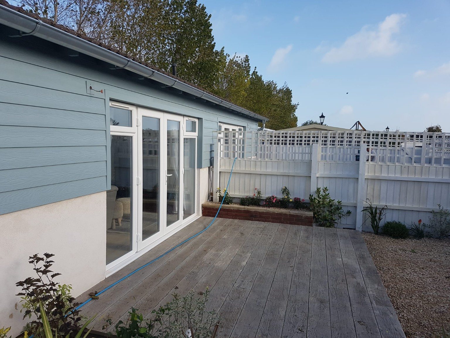 Finished blue cladding exterior with patio doors and decked garden area