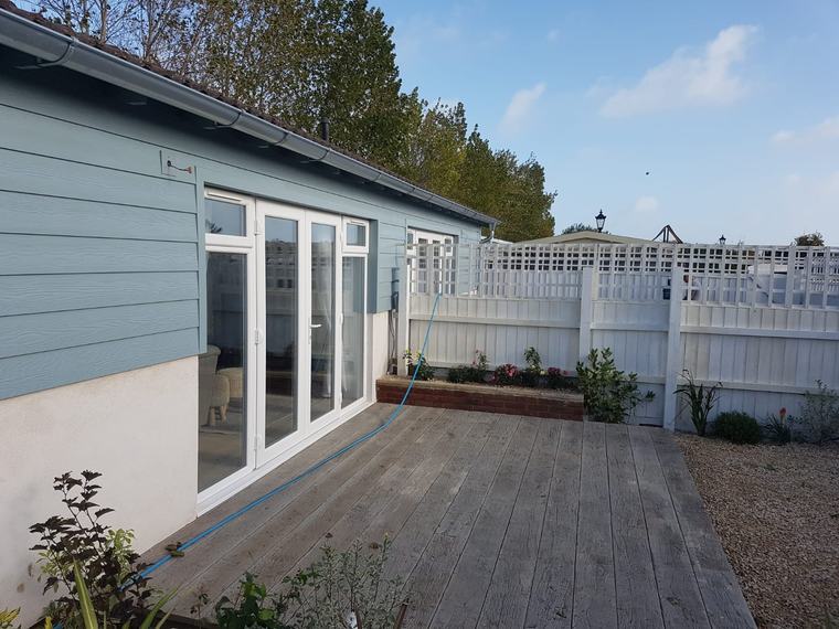 Finished blue cladding exterior with patio doors and decked garden area